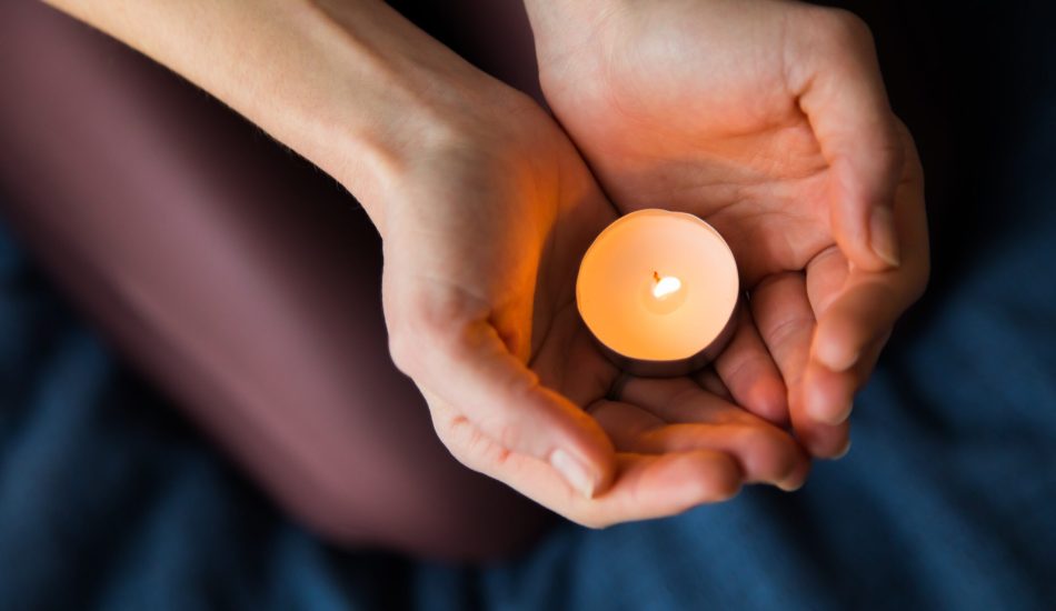 A selective focus closeup shot of female's hands holding a lit candle